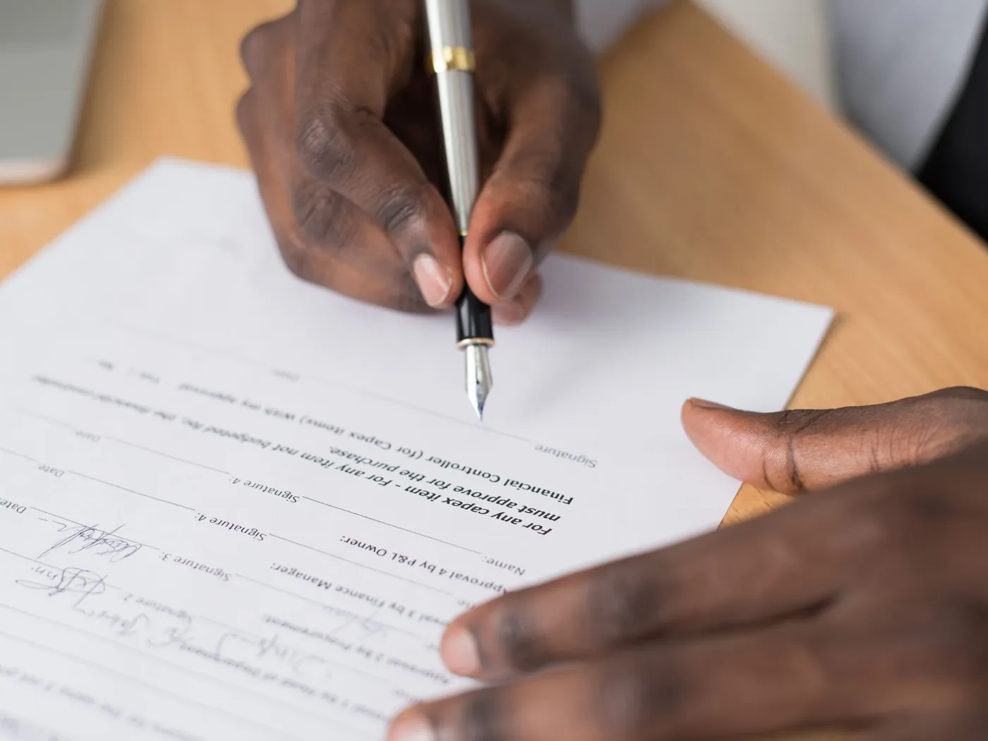 Close-up of a person writing on a printed form with a pen.