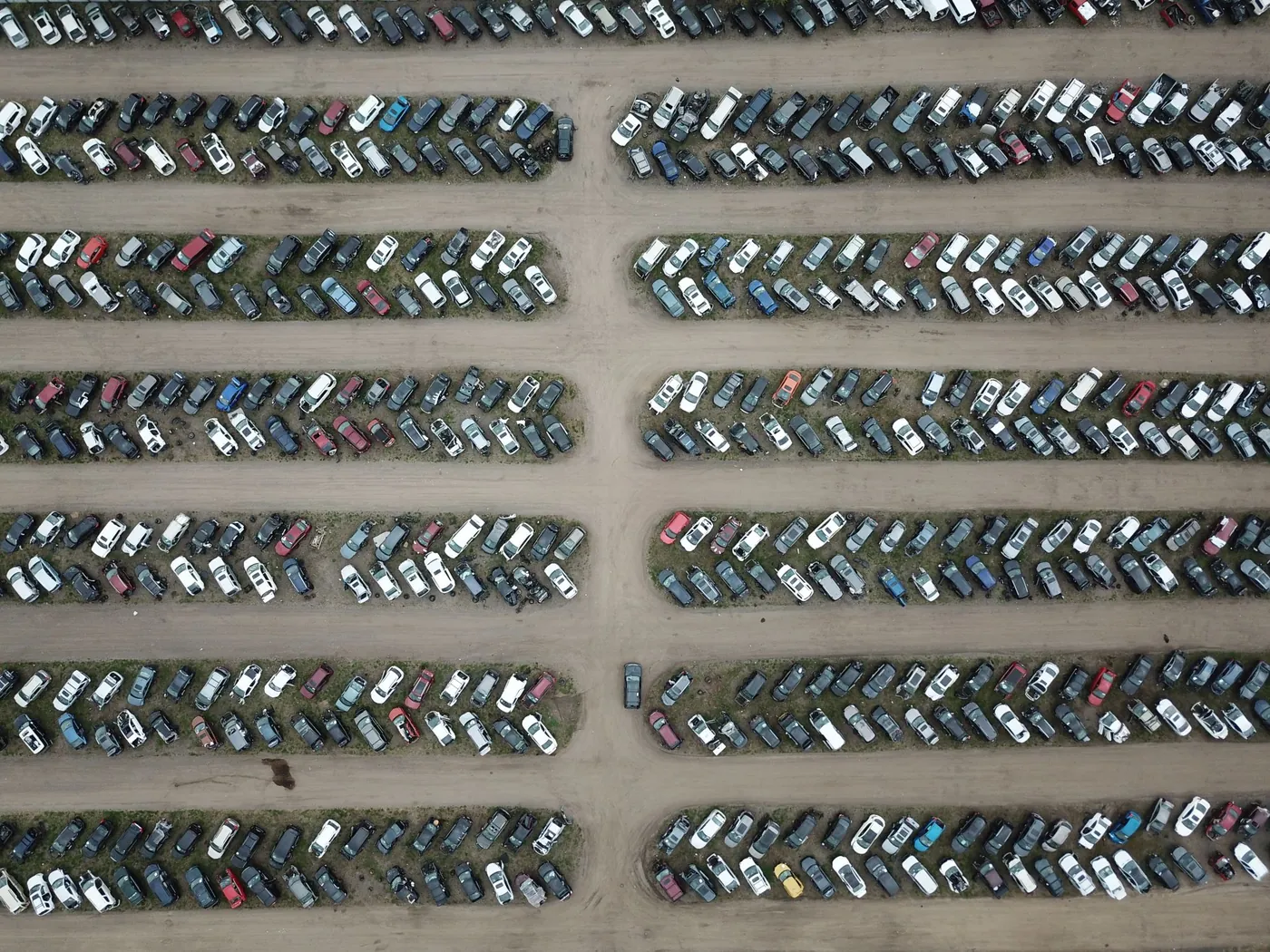 Aerial view of a large vehicle storage lot with tightly packed rows of cars.