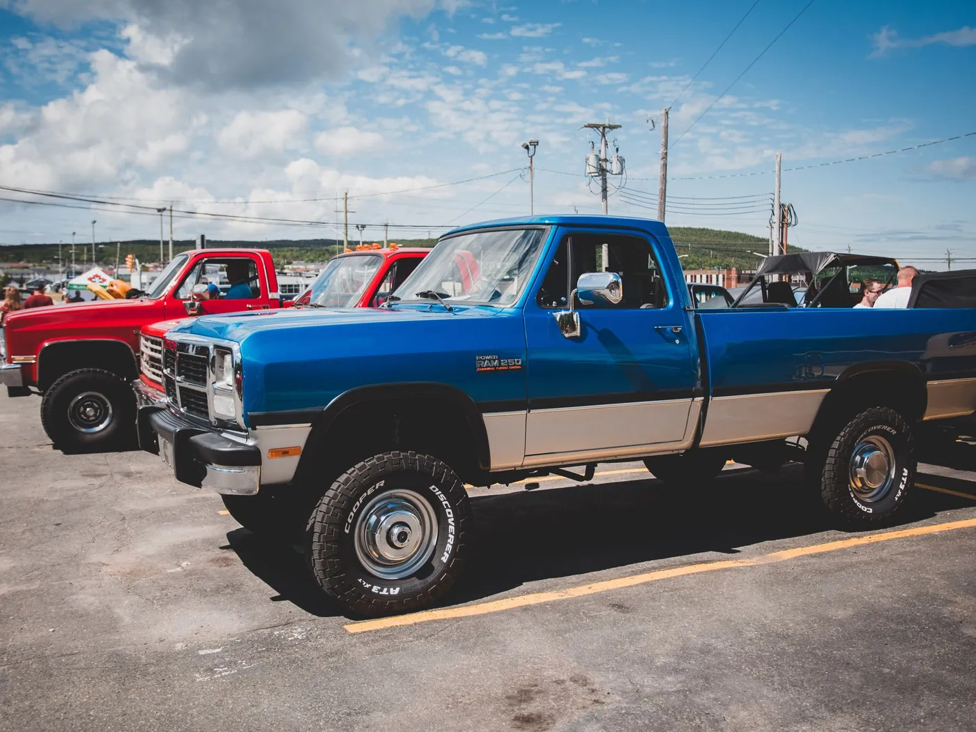 Two pickup trucks, one red and one blue, parked side by side in a lot.