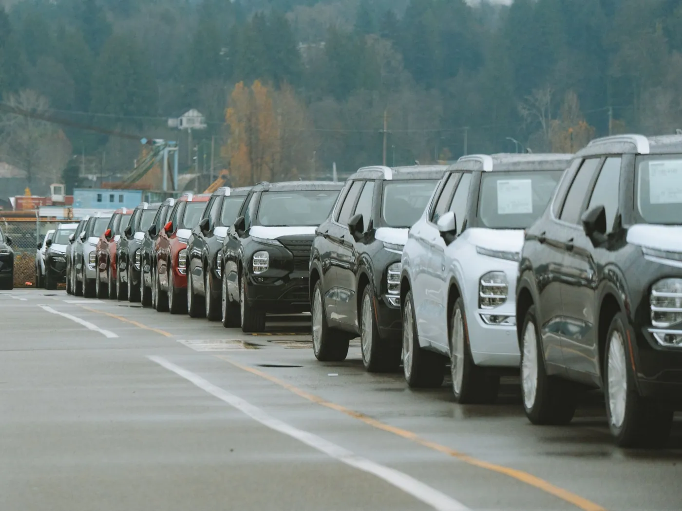 A long row of SUVs parked along a dealership lot on an overcast day.